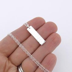 A modern take on a classic silver necklace. This necklace is specifically created to be just a whisper along your neck line, dainty, delicate, lightweight and beautiful. Perfect for layering with your favorite pieces.Elegant and dainty, this necklace consists of a vertical 1 inch Sterling Silver rectangle bar, hammered with my Classic texture and suspended from a  dainty 1.9mm Sterling Silver cable chain. The pendant is suspended just over 1 inch in length from the chain. Bar Size: 1 InchNecklac Elegant Silver Rectangular Bar Necklace, Minimalist Sterling Silver Necklaces For Layering, Minimalist Sterling Silver Layering Necklaces, Silver Minimalist Necklace With Rectangular Pendant, Minimalist Silver Rectangular Pendant Jewelry, Dainty Sterling Silver Bar Necklace, Minimalist Hammered Jewelry With Rectangular Pendant, Minimalist Sterling Silver Bar Necklace With Rectangular Pendant, Simple Silver Rectangular Pendant Jewelry