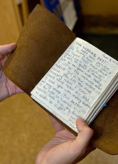 a person holding a book with writing on it and an article in the bottom right corner