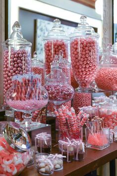 a table topped with lots of candy covered in pink and white candies next to a mirror