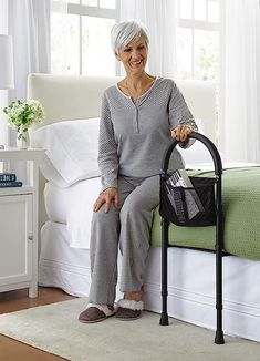 an older woman sitting on top of a bed next to a black bag and chair