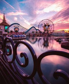 an amusement park at sunset with ferris wheel and roller coasters in the foreground