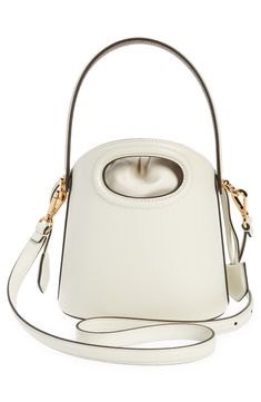 A dipped topline and oval cutout showcase the encased drawstring pouch of this structured leather bucket bag furnished with a top handle and removable strap. Drawstring closure Top carry handle; removable, adjustable crossbody strap Striped-twill lining Structured silhouette with flat base and protective metal feet Leather Imported Designer Handbags Designer White Bucket Bag With Top Carry Handle, Cream Bucket Bag With Handle Drop, Luxury White Bucket Bag With Top Handle, Luxury White Bucket Bag With Top Carry Handle, Modern White Bucket Bag With Gold-tone Hardware, Evening White Double Handle Bucket Bag, Cream Top Handle Bucket Bag With Detachable Handle, White Bucket Bag For Evening, White Leather Bucket Bag With Handle Drop