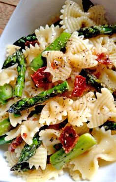 pasta with asparagus, sun dried tomatoes and parmesan cheese in a white bowl