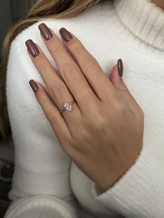 a woman's hand with brown nail polish and a diamond ring on her finger