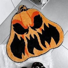 a rug with an orange and black pumpkin face on it next to two video game controllers