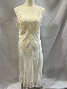 This lovely vintage Lady Love white slip dress with lace is from the 1930's/40's. (This item is dated to the best of my ability, so dates are approximations. However, I do have experience working and studying in the fashion/garment industry.) The straps are 3/8" wide and adjustable with metal sliders. There are 2 different styles of lace along the bodice edge and 3 different styles of lace along hemline that measures 4 3/4". There are 8 panels/gores for a shapely fit. CONDITION: Very good vintage pre-owned condition. I carefully examine every garment and do my best to disclose any imperfections and repairs. However, it is impossible to catch absolutely every flaw in a garment; please be understanding of the age of these vintage/antique garments and message me with any questions prior to pu Spring Formal Slip Dress With Lace Trim, Formal Feminine Slip Dress With Lace Trim, Summer Formal Slip Dress With Lace Trim, Fitted Lace Patchwork Slip Dress For Weddings, White Lace Trim Slip Dress For Evening, Fitted Slip Dress With Lace Trim For Wedding, Fitted Lace Patchwork Slip Dress For Daywear, Fitted Lace Trim Slip Dress For Wedding, Fitted Cream Slip Dress For Wedding Night