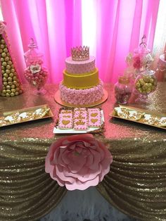 a table with pink and gold desserts, candy bars, and flowers on it