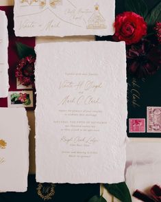 the wedding stationery is laid out on top of each other, with red flowers