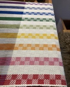 a multicolored table cloth on top of a wooden table with drawers in the background