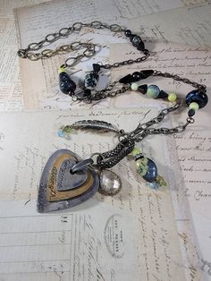 "Art Assemblage Necklace: I created the long necklace by building it around a Mixed Metal heart that says \"gorgeous strength, and spirit\" with some odd charms from salvaged jewelry.  There are stone and Czech glass beads, and brass feather charms, chips, chrystal charm and patinaed brass chains. The eclectic mix is very organic, natural and endearing. It measures 33 inches long with a 4 inch pendant that is adjustable with a lobster clasp."