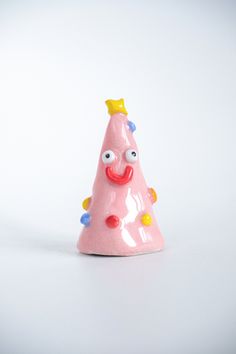 a pink plastic toy with a smiling face on it's side and a yellow crown on its head