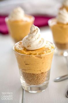 no bake mini pumpkin cheesecakes in small glass cups with whipped cream on top