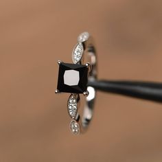 a black and white diamond ring sitting on top of a piece of metal with diamonds around it