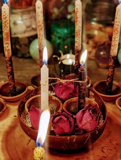 several candles are lit in small clay bowls with flowers on the table next to them