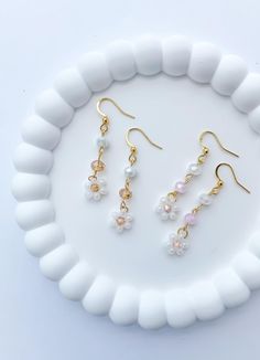 three pairs of earrings sitting on top of a white plate next to a pair of gold earwires