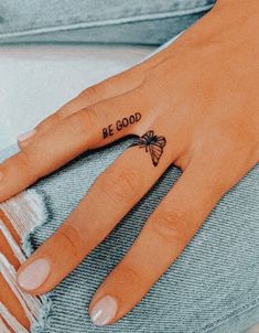 a woman's hand with a small butterfly tattoo on the ring finger that says be good