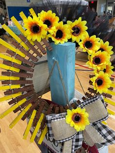 a blue vase with yellow flowers on top of a wooden table in front of a basketball court