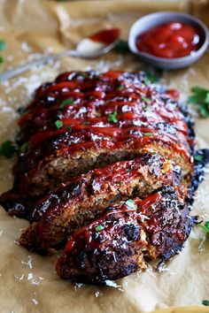 meatloaf with marinara sauce and parmesan cheese on parchment paper next to small bowl of ketchup