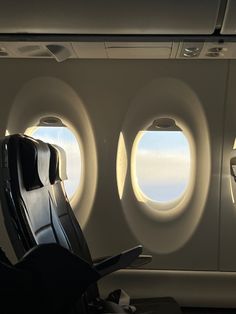 the inside of an airplane with three round windows and two seats in front of them