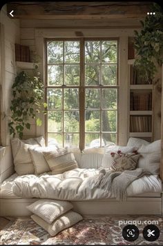 a white couch sitting under a window next to a book shelf with books on it