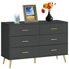 a black dresser with two vases and a picture frame on the top, sitting next to it