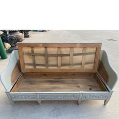 an old wooden box sitting on top of a cement floor next to a planter