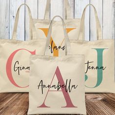 three personalized tote bags sitting on top of a wooden table