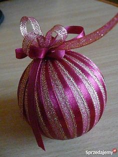 a pink ornament sitting on top of a table next to a red ribbon