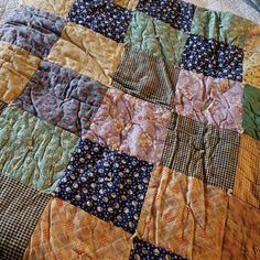 an old quilt is laying on top of a bed sheet that has been made into a blanket