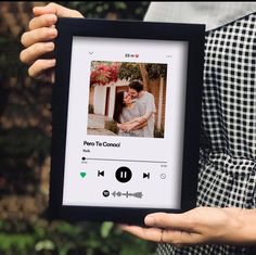 a person holding up a framed photo with an audio player on it's screen