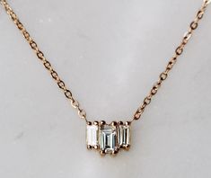 Inspired by the art deco architecture of the Empire State Building and Rockefeller Center, our "Empire" diamond baguette necklace has clean, sophisticated lines with as much sparkle as the top of the Chrysler Building! A perfectly elegant, dainty statement necklace! - 3 baguette diamonds (all SI GH quality or better), sides measure 3mm x 1.5mm, center measures 4mm x 2mm - Available in 14" - 15" - 16" -  17" - 18" inches  - Finished with a spring clasp - Available in 14K yellow, rose or white gol Classic Yellow Gold Baguette Cut Diamond Necklace, Gold Baguette Cut Necklace With Single Diamond, 14k Gold Baguette-cut Fine Jewelry Necklace, Elegant 14k Gold Baguette-cut Necklace, Luxury Necklaces With Baguette Diamonds, Square Pendant, Baguette Diamond Necklace, Baguette Necklace, Necklace Art Deco, Diamond Baguette