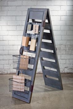 a ladder shelf with baskets on it next to a stuffed animal and other items in front of a brick wall