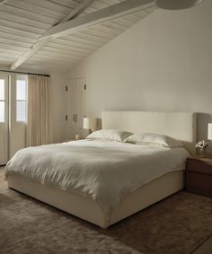 a large white bed sitting in a bedroom next to two lamps on either side of the bed