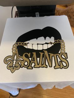 a white table topped with a black and gold logo on top of a wooden floor