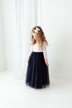 "This dress is just beautiful! It includes a delicate white lace bodice with a navy blue colored tulle skirt. The V Back with unfinished lace adds the perfect amount of boho chic look to this amazing dress. The lace sleeves are finished with the perfect amount of detail. It also includes a single flower sash that is removable. Perfect for your next special event. Nicolette's Couture is a family owned boutique based out of Dubuque, Iowa. We've had amazing success so far and believe our story is j Navy Blue Dress Outfit, Navy Blue Flower Girl Dresses, Kids Bridesmaid Dress, Flower Girl Dresses Navy, Blue Dress Outfits, Dubuque Iowa, Lace Flower Girl Dress, Long Sleeve Ball Gowns, Bridal Party Attire