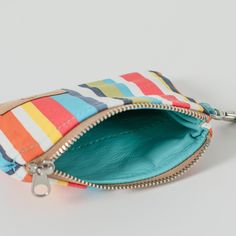 Experience luxury and style with this colorful striped, clip pouch. Its slim design allows for easy pocket access while providing ample space for your ID and cards. Add a touch of sophistication with the removable wristlet strap and carry it solo. Handcrafted by our team of women artisans in recovery, 100% of your purchase goes to provide job skills training and career development for the women who made it. Details 100% upcycled materials Dimensions: 5" x 4" Liner: Upcycled blue fabric Removable Multicolor Pouch Coin Purse For Everyday Use, Multicolor Zipper Coin Purse For Everyday, Multicolor Zipper Coin Purse, Multicolor Wristlet With Card Slots For Daily Use, Multicolor Coin Purse With Cell Phone Pocket, Everyday Multicolor Wristlet With Card Slots, Multicolor Wallets With Interior Card Slots, Multicolor Wallets With Interior Card Slots For Everyday Use, Multicolor Coin Purse With Zipper For Daily Use