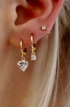 This CZ Heart Huggie ﻿is a fun yet sophisticated earring. These would look darling alone or stack with some of our studs to create a shiny layered look. Materials: Cz heart charm, gold plate brass huggies SKU: E1545G Three Hoop Ear Piercings, Gold Dainty Heart Earrings With Cubic Zirconia, Gold Cubic Zirconia Heart Earrings In Dainty Style, Dainty Gold Heart Earrings With Cubic Zirconia, Dainty Huggie Earrings With Heart Charm, Gold Heart Cartilage Earrings For Everyday, Everyday Gold Heart Cartilage Earrings, Gold Heart-shaped Cartilage Earrings, Gold Plated Huggie Earrings With Heart Charm