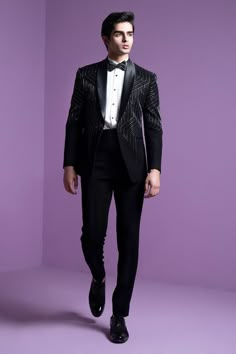 a man in a tuxedo and bow tie is standing against a purple background