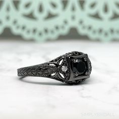 M A T E R I A L S ~ Solid Sterling Silver ~ Black Rhodium S T O N E S Cruelty Free ~ Simulated Black Diamond ~ Center Stone : 0.45ct ~Side White Diamonds: 0.12ct D I M E N S I O N S ~ Band: 3.00mm ~ Setting: 5.75mm Height 9.00mm Width R I N G C A R E ~ Simple instructions to care for the ring is not expose your jewelry to chemicals like bleach, chlorine, hairspray, to avoid chemical reactions or breakdown of materials. (Just as you would with any jewelry) ~ Try not wear your jewelry in the showe Classic Black Rings For Anniversary, Classic Black Jewelry With Center Stone, Formal Black Rings With Black Diamonds, Black Diamond Ring With Accent Stones, Classic Black Ring With Halo Setting, Classic Black Rings With Accent Stones, Formal Black Rings With Accent Stones, Classic Black Jewelry With Accent Stones, Black Heirloom Ring With Center Stone