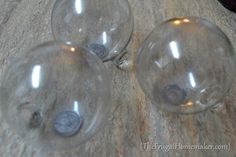 three clear glass orbs sitting on top of a wooden table next to each other