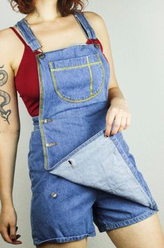 RENEWED VINTAGE Blue Bronze Denim Dungarees SkortsSize S, see below for measurementsBrand: Dixie Blues, Authentic Original100% cottonside button placketwith breast pocketlooks like a dungaree dress at first glancethere are shorts under the skirtthis vintage piece was painted with shimmering gold textile paintnow a real eye-catcher and absolutely unique pieceVintage condition: VERY GOOD, only a small material defect on the backWaist size: approx. 33cmLength: approx. 82 cm (but can be changed by t Onepiece Overalls, Blue Utility Shortalls For Spring, High Waist Cotton Medium Wash Shortalls, High Waist Medium Wash Cotton Shortalls, High Waist Blue Cotton Overalls, Blue Bib Front Denim Jumpsuit With Pockets, Blue Denim Bib Front Jumpsuit With Pockets, Blue Denim Jumpsuit With Bib Front And Pockets, Utility Denim Bottoms With Bib Front