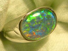 "As a rule the very best & highest quality stones are strictly reserved for our 14ct Gold range. Occasionally I set a few of the very best stones in the Sterling Silver range, this is one of those occasions. If you are prepared to pay a premium for the very best quality Opal , without the extra expense of a Solid Gold setting, this could suit. The ring is made from Sterling Silver & is fully \"J\" backed. The Gem Plus grade Triplet Opal is 14x10mm Oval & of the highest quality. The design featur Modern Oval Opal Ring For Formal Occasions, Classic Green Oval Opal Ring, Classic Oval Opal Ring With Polished Finish, Classic Oval Rings With High Luster, Classic Oval Ring With High Luster, Classic Oval High Luster Ring, Classic Oval Opal Ring Collectible, Green Oval Opal Ring For Formal Occasions, Classic Oval Hallmarked Opal Ring