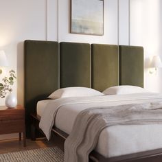 the headboard of a bed is made up with white linens and green fabric