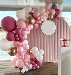 a bunch of balloons that are on the ground in front of a wall with pink and white colors