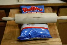 a bag of ruffles sitting on top of a wooden table next to a rolling pin