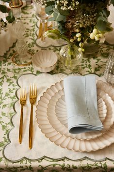 a table set with plates, silverware and flowers