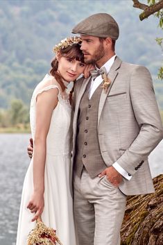 a bride and groom standing next to each other in front of a lake with trees