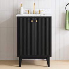 a black cabinet with two gold knobs and a white marble top in a bathroom