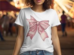 Introducing the Pink Bow Graphic T-Shirt, a charming addition to any wardrobe with its adorable pink bow design. Perfect for those who love the cute coquette aesthetic, this coquette bow shirt embodies the soft girl era with its delicate ribbon details. Ideal for girlie girls, this bow shirt is a versatile piece that pairs well with any outfit. Whether you're looking for a gift for mom, daughter, or simply treating yourself, this preppy bow t-shirt is sure to delight. Embrace the coquette vibe w Casual Summer T-shirt With Pink Bow, Feminine Cotton Short Sleeve T-shirt, Feminine Pink Crew Neck T-shirt, Casual Short Sleeve T-shirt With Pink Bow, Cute Pink T-shirt With Custom Print, Kawaii Crew Neck Tops For Gifts, Kawaii Crew Neck Tops As Gift, Kawaii Crew Neck Top, Cute Cotton Tops For Gifts