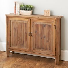 a wooden cabinet sitting on top of a hard wood floor next to a white wall